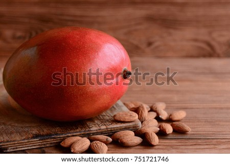 Ripe tasty mango and peeled almond on a brown wooden background with empty space for text. Raw juicy mango fruit and nuts photo. Fresh healthy food