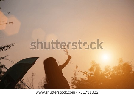 A silhouette of a girl praying over a beautiful sky background.