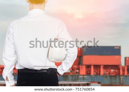 Construction engineer supervising work with container background in the construction site with blue sky floor.