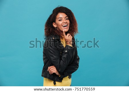Photo of cheerful beautiful young african woman standing isolated over blue background. Looking camera.
