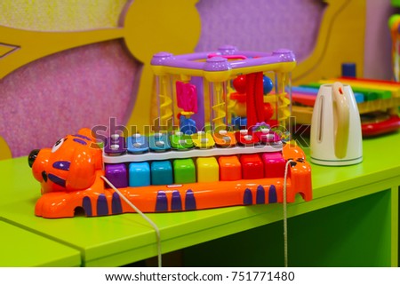 Rainbow colored xylophone on the table among toys in baby room.