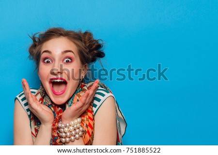 emotions, people, beauty, fashion and lifestyle concept - The portrait of young woman with shocked facial expression, over blue background