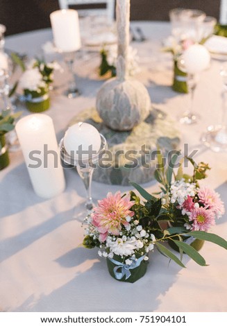 Wedding table at reception with flower decorations, candles and white tableware