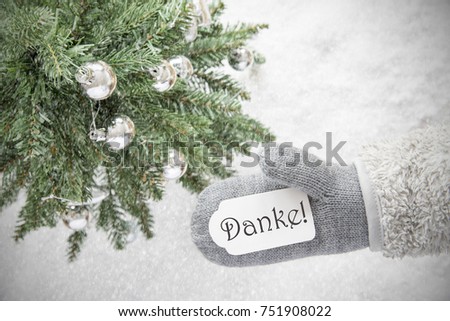 Glove With Label With German Text Danke Means Thank You. Green Christmas Tree With Silver Balls On Snow In Background. Seasonal Greeting Card With Snowflakes.