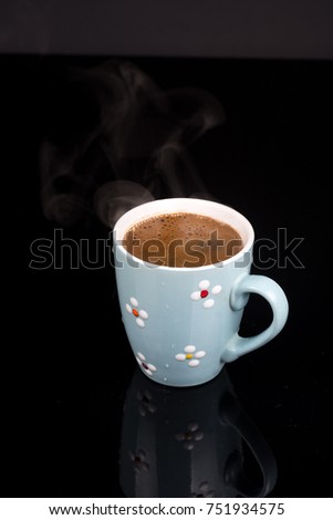 Cup of coffee isolated above black background with reflections.