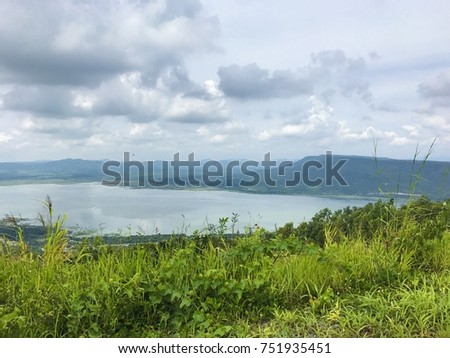 The reservoir view on Lam Ta Kong Dam at Nakhon Ratchasima, Thailand. Scenic Countryside with reservoir, rain cloud and the Flat-Peak Mountain background. 