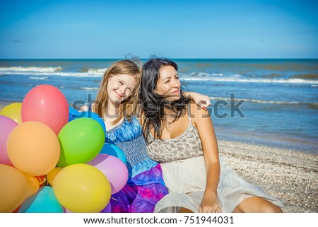 Happy family. Loving mother with seventeen-year-old daughter with Down syndrome on the beach With balloons. Positive human emotions, feelings.