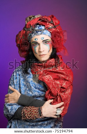 Young man in creative eastern image in red turban and with artistic make-up
