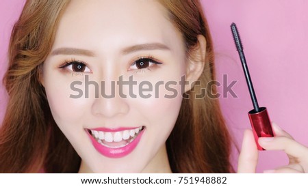beauty woman take mascara on the pink background