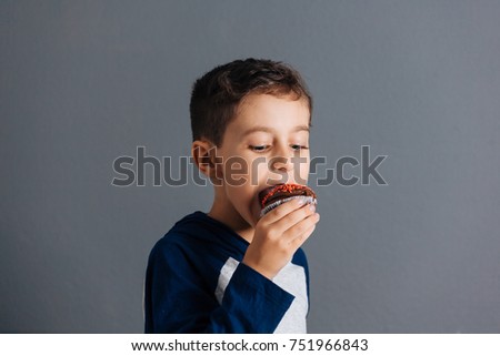 Brazilian child eating cupcake on gray background