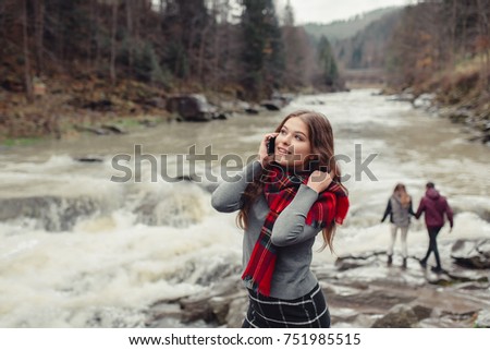 A young stylish brunette hipster woman in nature,talking  with her smartphone. Girl with mobile phone in hand
