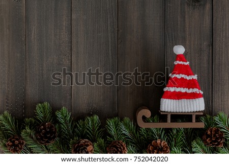 Christmas fir tree branches and santa clause hat on dark rustic wooden background with copy space for text