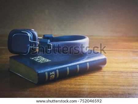  holy bible with head phone on wooden table with window light in the morning, copy space