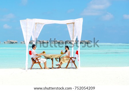 Asian couple enjoying romantic luxury lunch setting at tropical beach in Maldives Royalty-Free Stock Photo #752054209