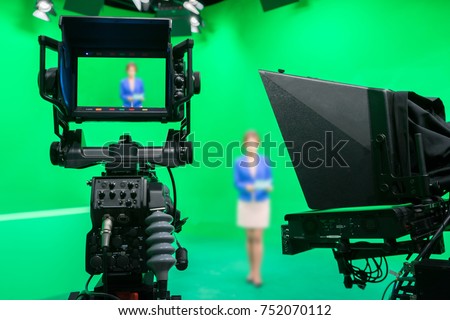 Blur image of newscaster or announcer preparing to record program in broadcast television virtual greenscreen studio room with professional cameras.