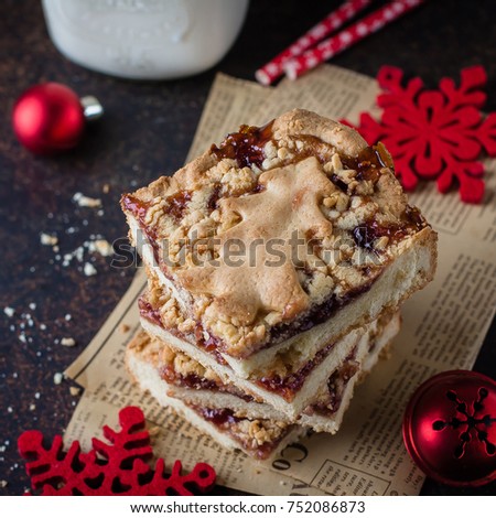Homemade shortcrust raspberry pie with crumble and Milk Mason Jar Glass on dark stone concrete table background. Jam Bars Snack Christmas Food Dessert. Winter Cake with Festive Decoration