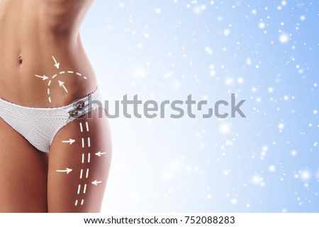 Fit and sporty woman with beautiful and slender body over seasonal Christmas background with winter snow. Health, diet and sport concept.