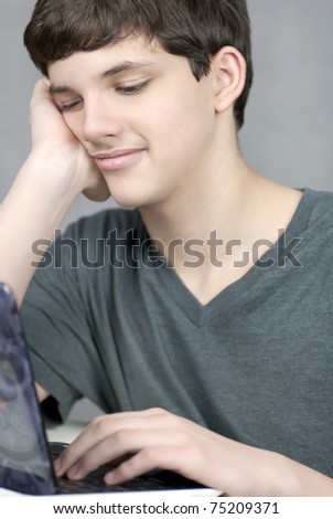 Close-up of a sleepy teen working on his laptop..