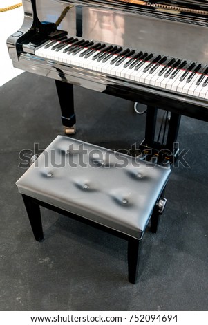 Grand piano with black leather chair on black carpet