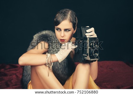 Woman with retro hair, makeup and old camera. beauty, retro look, pinup fashion. 