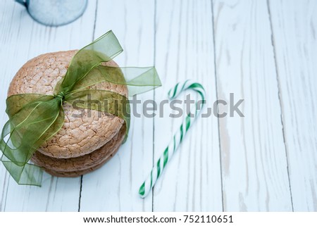 
almond cookies tied with green ribbon and lollipop on white wooden background