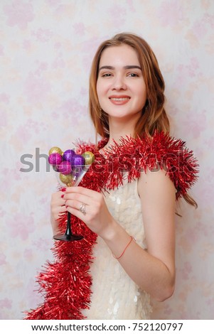 The girl or teenager in a brilliant dress and red tinsel having fun, smiling and throwing confetti and glitter, celebrates New Year 2018, Christmas, birthday. The emotions of happiness, joy, pleasure.