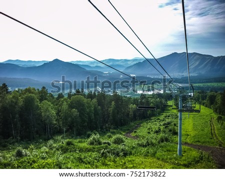 Emtpy chairlift in ski resort. Shot in summer with green grass and no snow. Smoke on the mountains.
