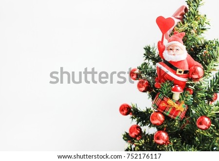 Christmas Tree Decorated with Red Toys, Ribbon and Santa Claus Figurine Holding a Heart on White Background. Holidays Greetings Card with Empty Copy Space, New Year and Christmas Celebration Theme.