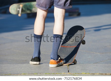 Skateboarding - detail of skateboard and legs with trainers.