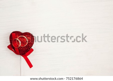 wedding rings on a red shiny heart