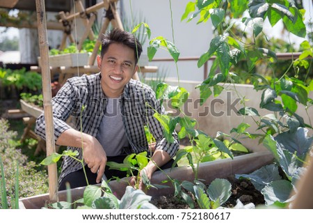 happy asian male doing gardening activity at his garden Royalty-Free Stock Photo #752180617