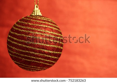Red Christmas toy with gold stripes on a red background. New Year, christmas background.