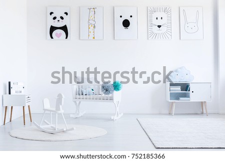 White rocking horse on carpet in baby's bedroom with cupboard and white cradle with pompons