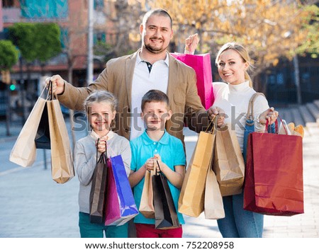 Young happy smiling parents with two teenagers going for a shopping outdoors