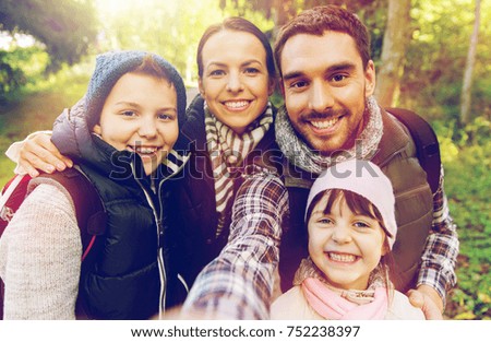 travel, tourism, hike and people concept - happy family with backpacks taking selfie and hiking