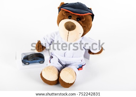 Brown toy  bear with toy car and notebook on white background.