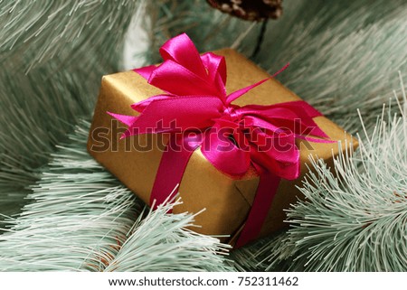 A gift with a red bow lies on a Christmas tree