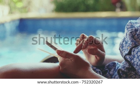 Businesswomen hands using smartphone by the swimming pool.