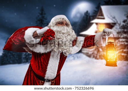Old santa claus with sack of gifts with lamp in hand of orange light. Landscape of mountains with big moon on dark sky. Snowflakes decoration. 