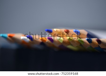 A pack of multicolored pencils on a dark gray background close up