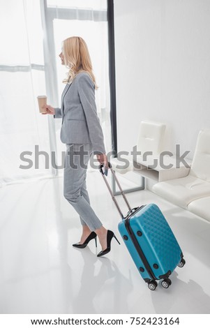 businesswoman with luggage and coffee to go going on trip