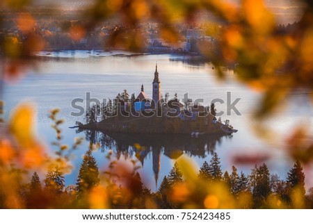 Bled, Slovenia - Aerial sunrise view of Lake Bled and Pilgrimage Church of the Assumption of Maria taken from Ostrica viewpoint at autumn. Framed with autumn foliage