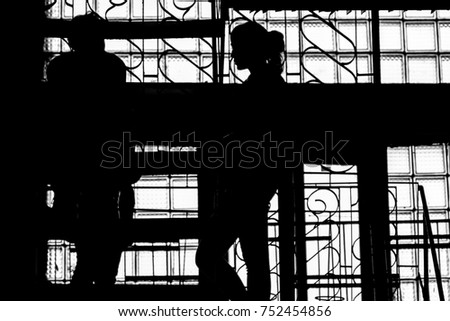 A photo. Two people are talking on the stairwell. Silhouettes, backlight.