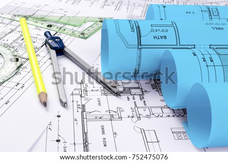 Architectural blueprints and blueprint rolls and a drawing instruments on the worktable. Drawing compass, plans. Civil Engineering, Construction background.