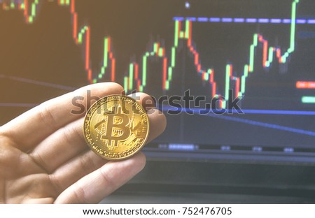 Hand holding a Bitcoin coin in front of a modern black notebook . Close-Up photo Bitcoin , exchange virtual value, crypto digital money . Background Live Stock trading through internet . 
