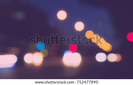 Blurred photo of town cars driving on road. Big circles , bokeh, from the evening night lights. The photo concept can be used widely as backgrounds , banners.