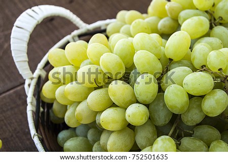 Fresh bunches of grapes in a basket on a wooden floor