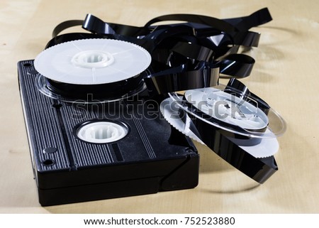 Image on video tape. Videotape tape wound on spools. Wooden table, black background.