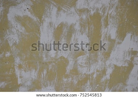 Washed watercolor white paint over yellow paint on concrete surface. 