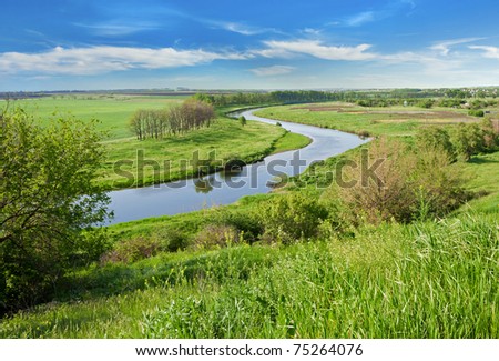 Rural landscape. Green field against the river and blue sky